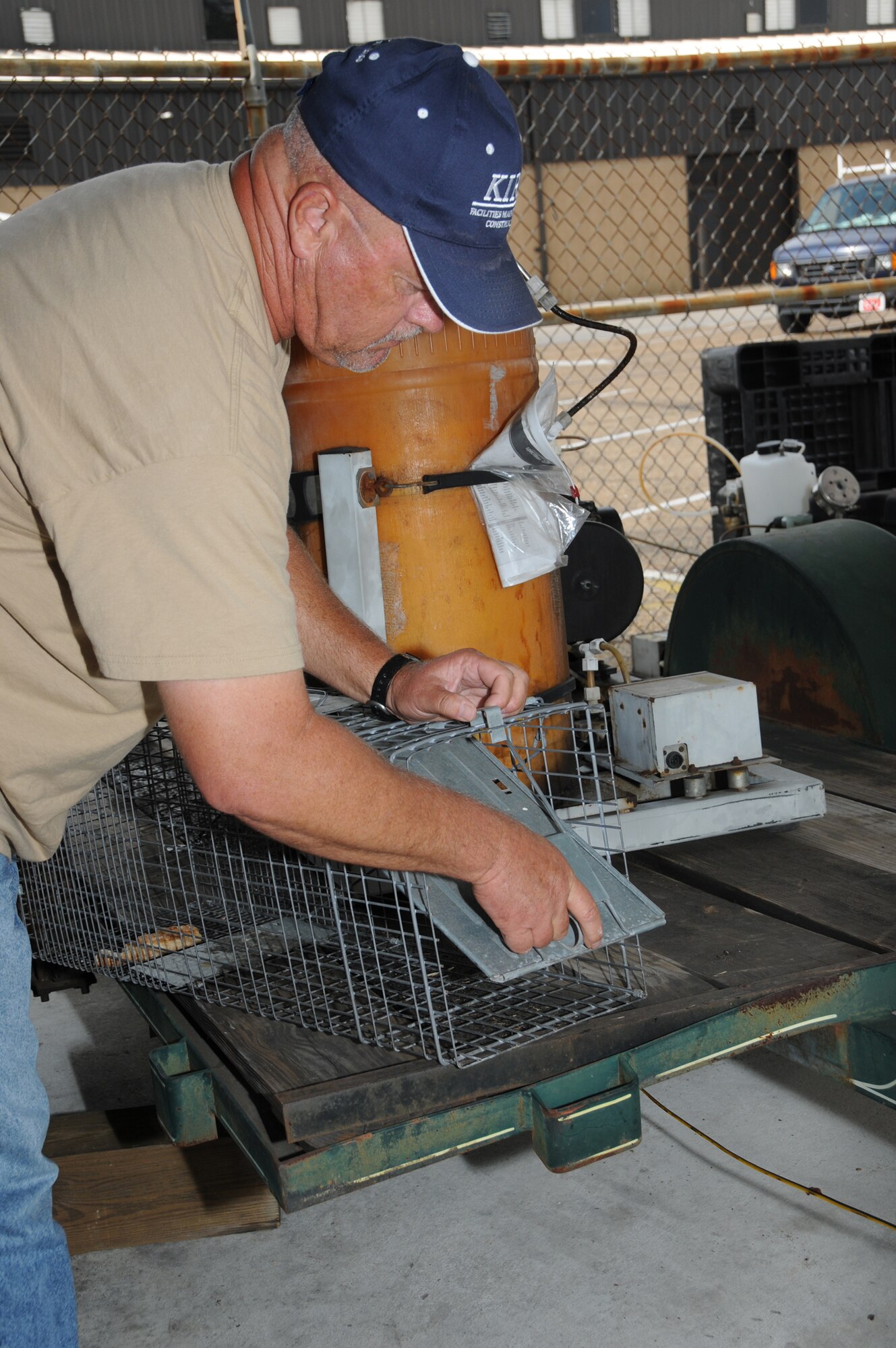 Mr. Thomas sets a trap to catch raccoons.  (U.S. Air Force photo by Kemberly Groue)