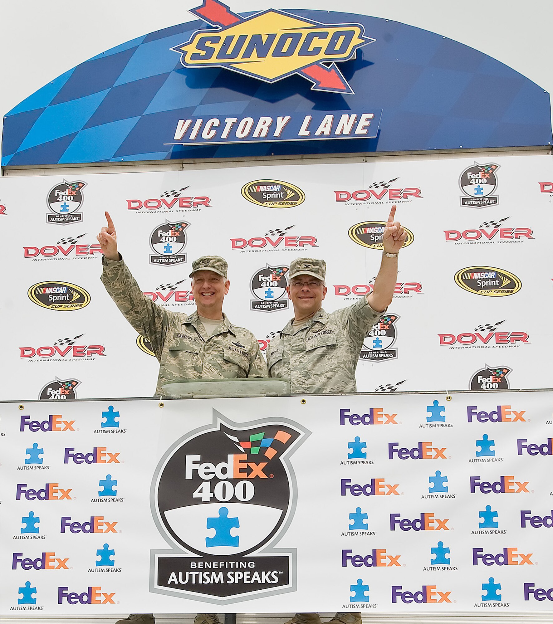 Col. Mark Camerer (left), 436th Airlift Wing commander, and Col. Randal Bright, 512th Airlift Wing commander, pose at the podium in Victory Lane May 15, 2011, at Dover International Speedway, Del. The Colonels were among the servicemembers able to enjoy NASCAR at the infield. (U.S. Air Force photo by Airman 1st Class Jacob Morgan)