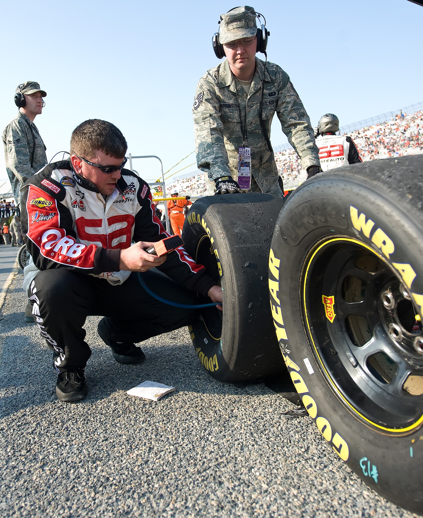 Kevin Gravitte, Red Horse Racing No. 13 tire carrier and tire specialist, and Staff Sgt. William Harrington, 436th Force Support Squadron food service supervisor, work together to check the pressure of the No. 13 truck’s tires May 13, 2011 at Dover International Speedway, Del.  These tires were taken off at the first pit-stop of the Lucas Oil 200. (U.S. Air Force photo by Airman 1st Class Jacob Morgan)