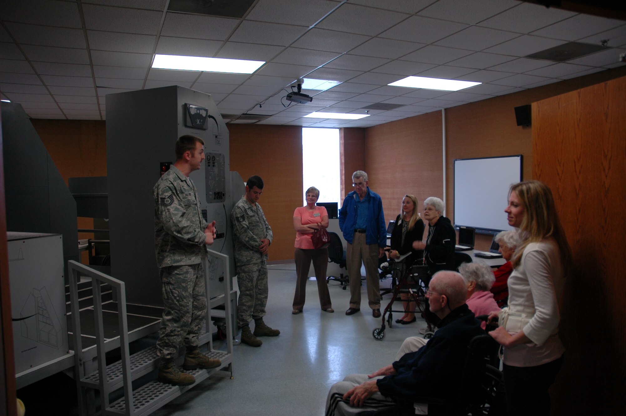 Technical Sergeant Higgins shows members of the Sweetgrass Retirement Village a replica of the C-17's cockpit, and explains how it's used to help train the maintenance crews.