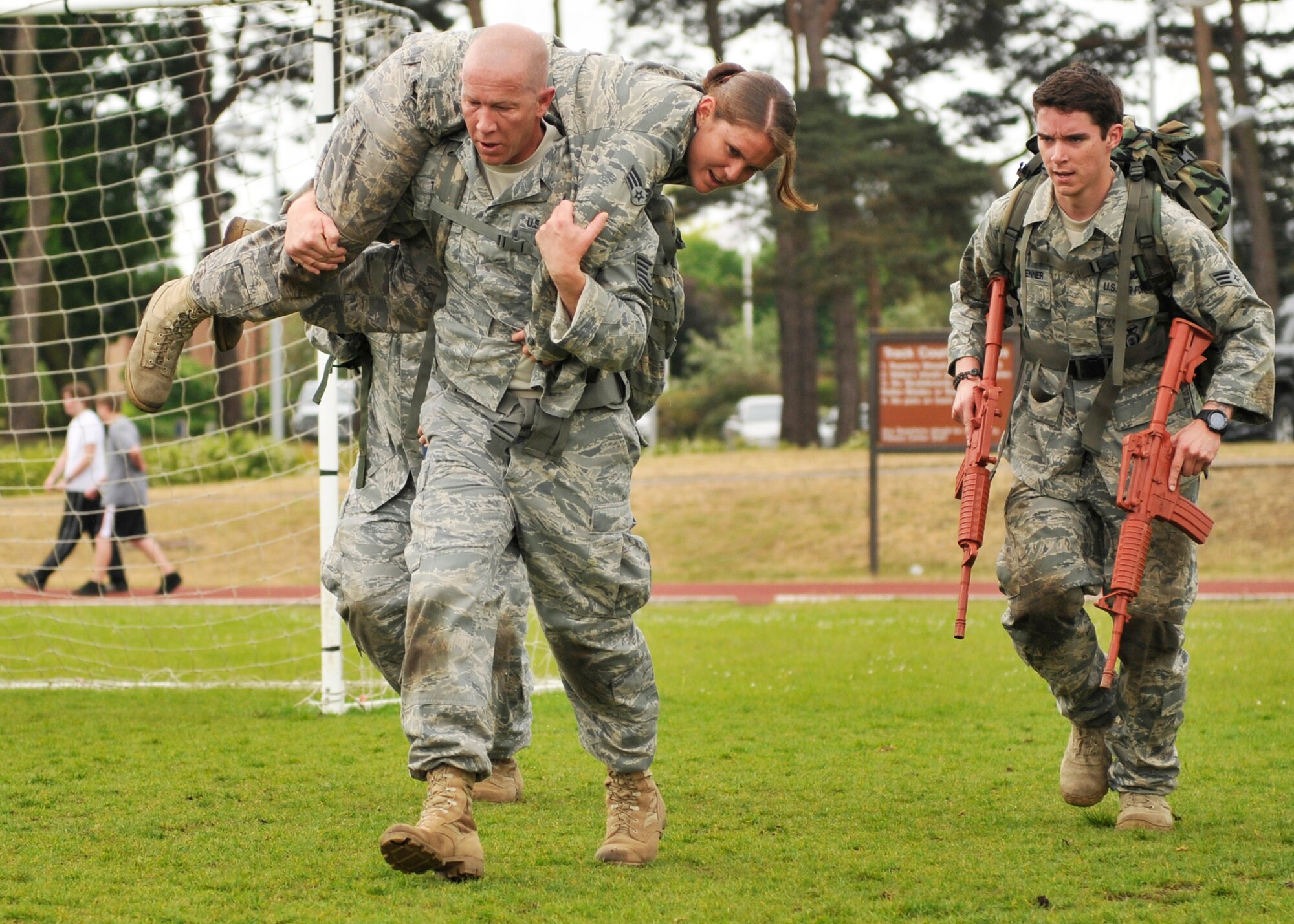 ROYAL AIR FORCE LAKENHEATH, England – A 48th Security Forces Squadron Airman performs a fireman carry as his teammate carries M-16 trainer weapons during the the 5K Combat Ruck March Challenge on May 17, 2011. This is one of several events that will be held during National Police Week at RAF Lakenheath to honor police officers. The challenge required the teams to race between four checkpoints: 25 push-ups, high crawl, memory game and fireman carry. (U.S. Air Force photo/Senior Airman Tiffany M. Deuel)
