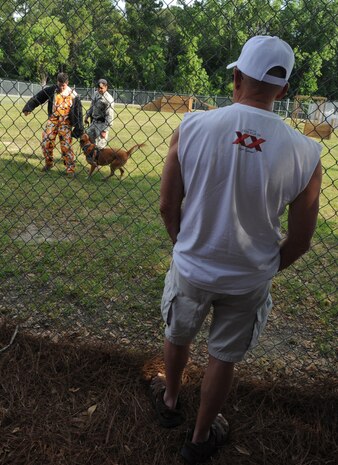 Bob Wallum watches a K-9 demonstration given by dog handlers, Senior Airman Joel Patterson, Staff Sgt. Fazal Munshi and military working dog Ardon on Joint Base Charleston, May 14.  Mr. Wallum is one of 32 veterans who attended the 50-year reunion of the 50th Air Police Squadron's K-9 section which was assigned to Hahn Air Base, Germany during the 1960s. Airman Patterson and Sergeant Munshi are assigned to the 628th Security Forces Squadron. (U.S. Air Force photo/ Staff Sgt. Nicole Mickle)  