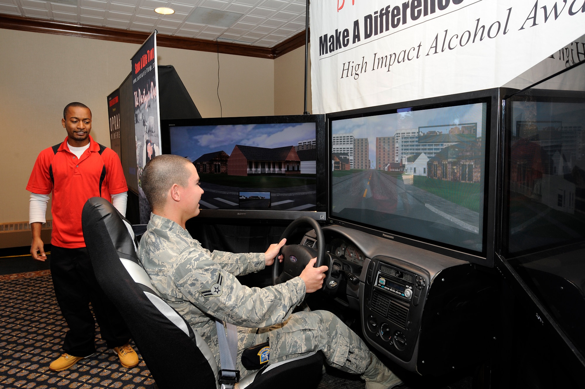 Airman 1st Class Robert Victor Smith, 721st Security Force Squadron (front), takes a spin behind the wheel of a drunken driving simulator May 13 in the Peterson Air Force Base Club while Jeremiah Newson, a Save a Life Tour manager (rear) tries to distract him. The simulator is programmed to respond as if a drunken driver was in control. The tour, which was brought to Peterson AFB in conjunction with the 21st Space Wing’s 101 Critical Days of Summer safety campaign, also included a video and a Save a Life Tour alcohol survey. In the summer months, between Memorial Day weekend and Labor Day weekend, safety mishaps tend to be high. The 21st SW’s campaign aims to draw special attention to safety with events and safety days throughout the summer. (U.S. Air Force/photo by Craig Denton)