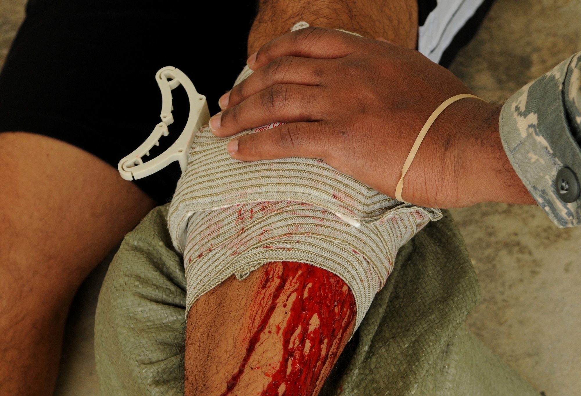 An Airman applies pressure to a mock gunshot wound on a moulage victim after a scenario involving an active shooter during a local operational readiness exercise, May 17 at Kadena Air Base, Japan. Scenarios during the LORE are used to strengthen responses of Airmen in case of real-world emergencies. (U.S. Air Force photo/ Airman 1st Class Jarvie Z. Wallace)