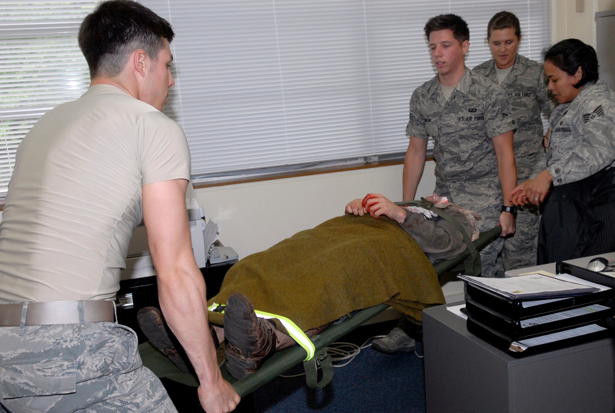 Airmen carefully move a "victim" of a gunshot wound onto a stretcher as part of a scenario simulating an active shooter during the Local Operations Readiness Exercise, May 17. The LORE, Beverly High 11-04, is a week-long exercise that prepares Airmen for possible real-world situations. (U.S. Air Force photo/ Airman 1st Class Tara A. Williamson)