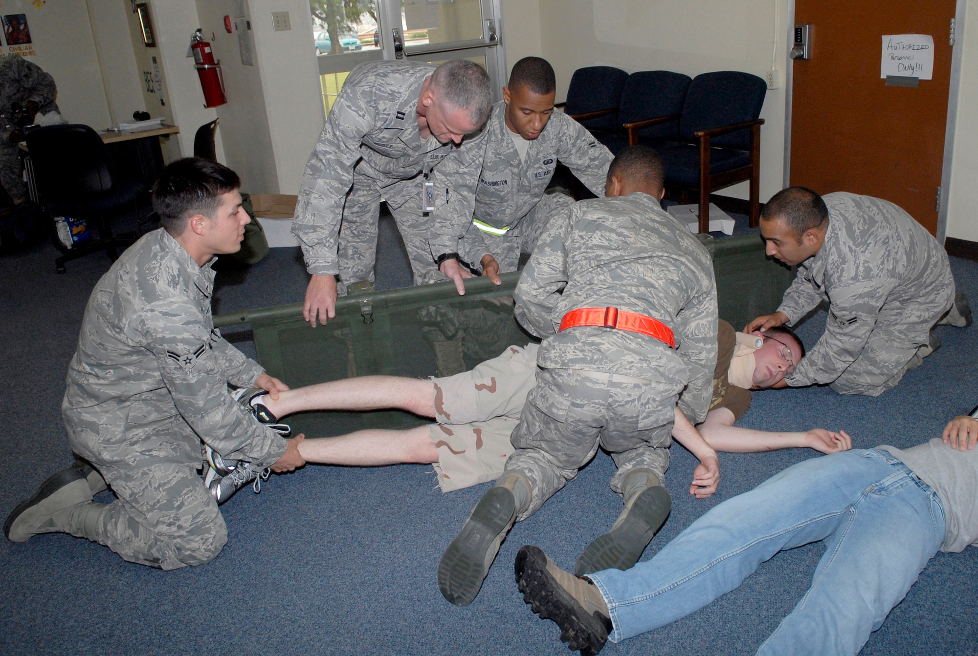 Airmen carefully move a "victim" of a gunshot wound onto a stretcher as part of a scenario simulating an active shooter during the Local Operations Readiness Exercise, May 17 at Kadena Air Base, Japan. The LORE, Beverly High 11-04, is a week-long exercise that prepares Airmen for possible real-world situations. (U.S. Air Force photo/ Airman 1st Class Tara A. Williamson)