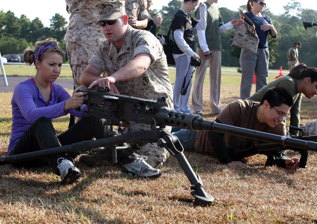 Cpl. Steve Stahl, a radio technician with 8th Communication Battalion, II Marine Expeditionary Force, shows a Marine spouse how to aim down the sights of a 50 Caliber Machine Gun during Jayne Wayne Day, May 18, 2011.  To ensure the spouses got the most realistic view into their husbands Marine Corps experience, they learned how to handle and fire a variety of the weapons used by Marines.