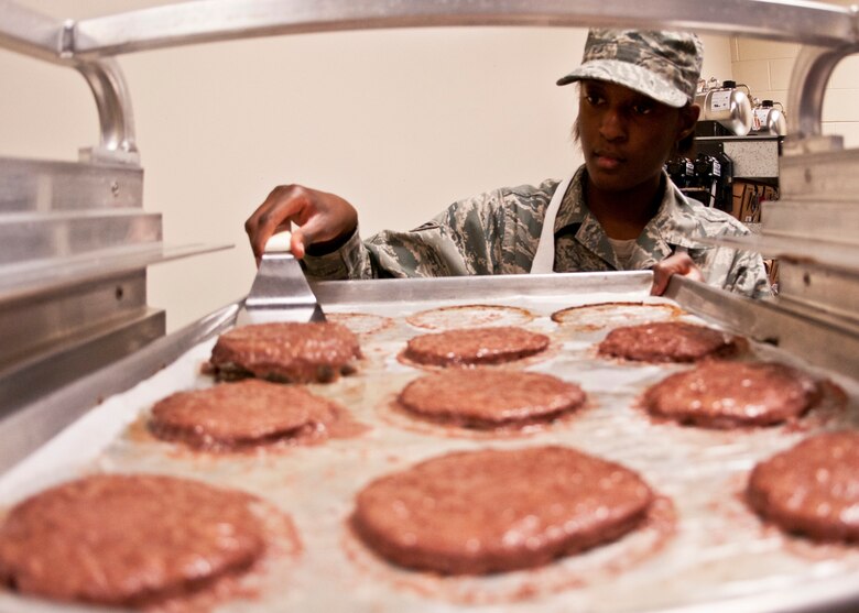 Senior Airman Asia Martin removes the burgers from a tray before taking them out to the snack line during the May unit training assembly at Duke Field.  Recently, the 919th FSS dining facility picked up its sixth John L. Hennessy award since 2000.  (U.S. Air Force photo/Tech. Sgt. Samuel King Jr.)