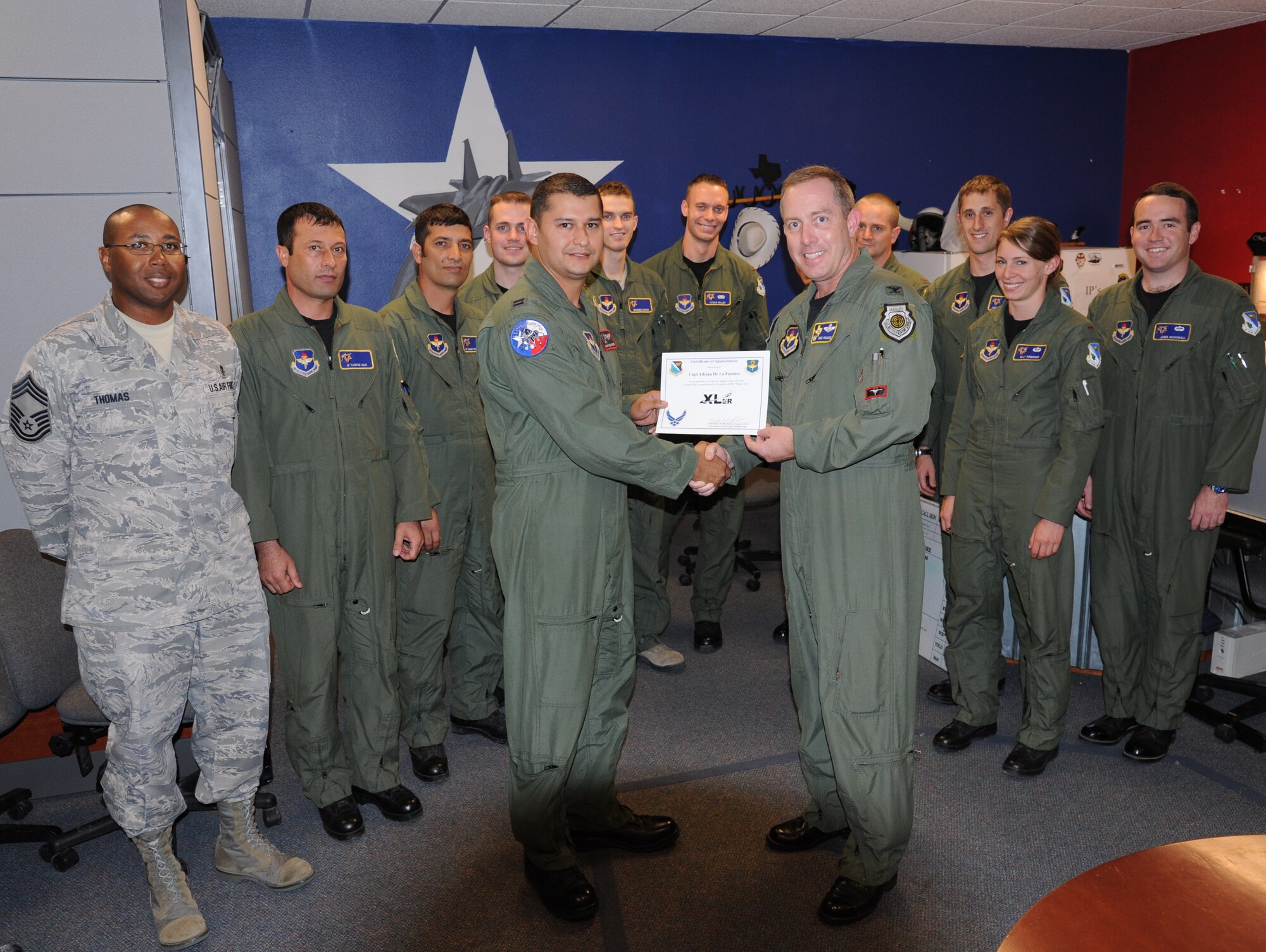 LAUGHLIN AIR FORCE BASE, Texas – Captain Adrian De La Fuentes, 84th Flying Training Squadron, poses with Col. Michael Frankel, 47th Flying Training Wing commander, Chief Master Sgt. Russell Thomas, 47th Medical Group superintendent, and fellow members of his squadron after being presented the XLer of the Week award here May 11. The XLer is a weekly award chosen by wing leadership and given to those who consistently make outstanding contributions to Laughlin and their unit. (U.S. Air Force photo by Airman 1st Class Blake Mize)
