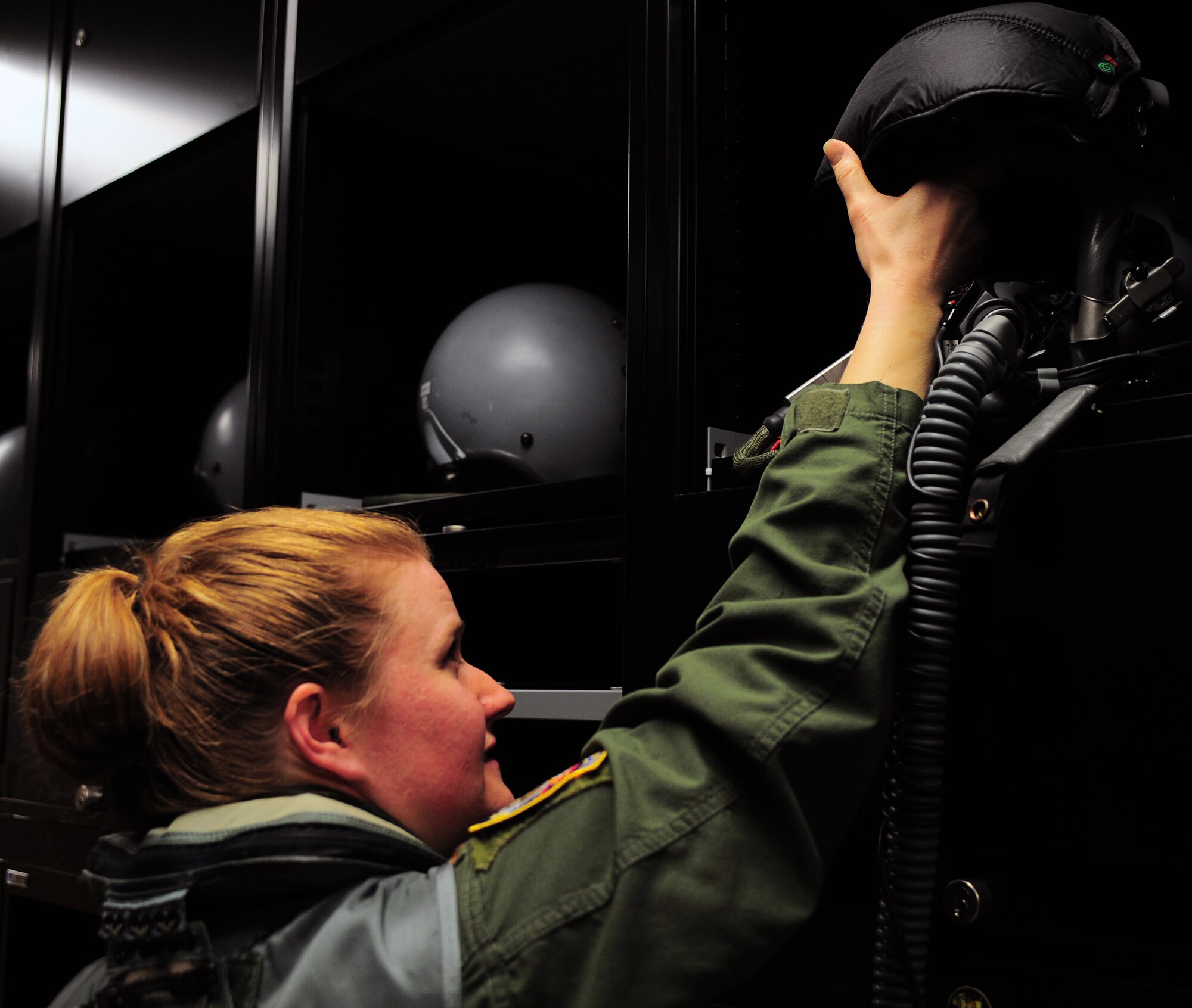 Maj. Jaime Nordin, an F-16 Fighting Falcon pilot in the 79th Fighter Squadron at Shaw Air Force Base, S.C., grabs her helmet from her locker March 26, 2011. The Air Force has had women in fighter pilot roles since 1993. (U.S. Air Force photo/Airman 1st Class Daniel Phelps)