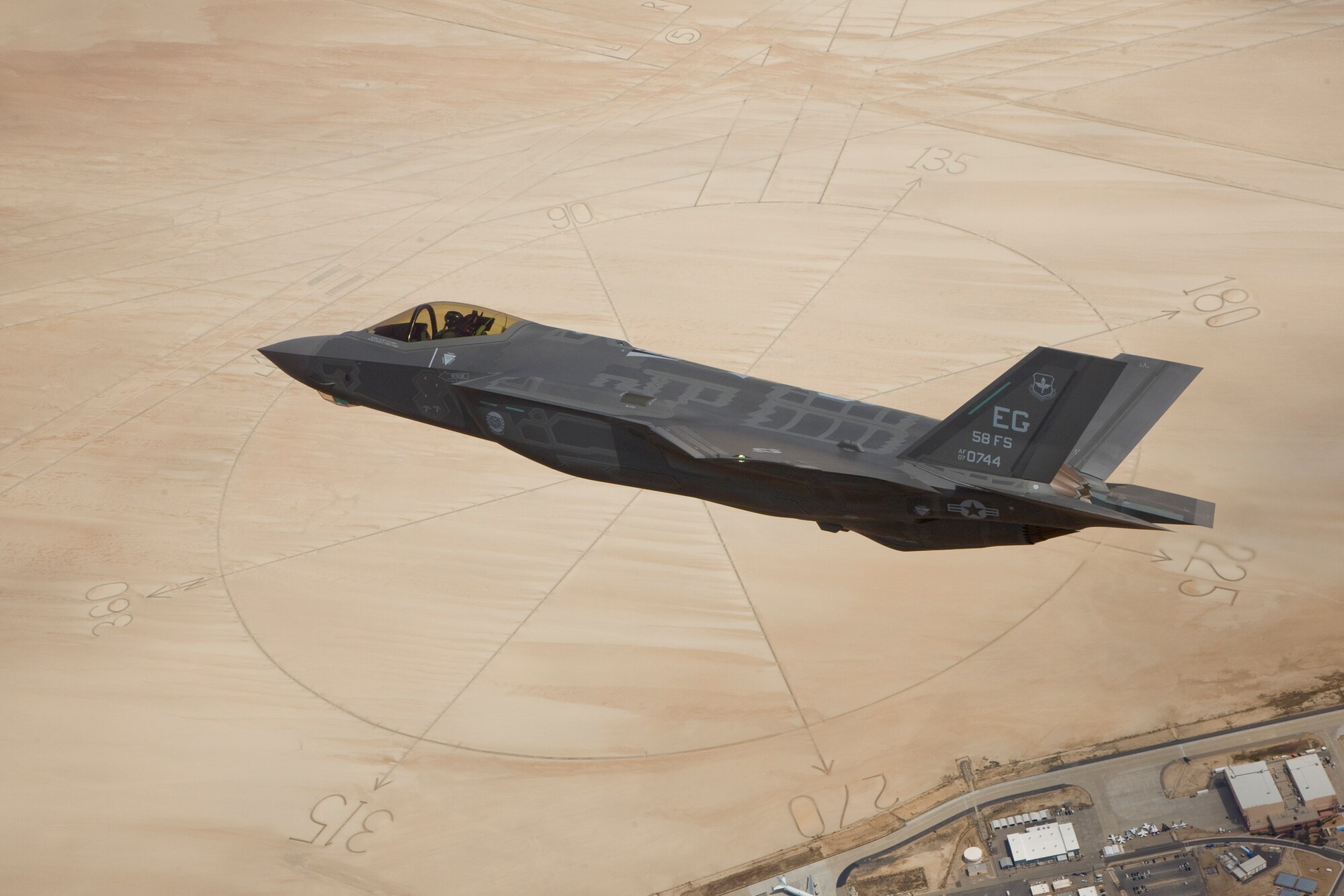 The second production model F-35A Lightning II aircraft flies above the compass rose of Rogers Dry Lakebed at Edwards May 13. The aircraft, designated AF-6, ferried to Edwards from Naval Air Station Fort Worth, Texas, Joint Reserve Base following the Air Force formally accepting the fighter into its inventory the day before. The first production jet, AF-7, was delivered to Edwards May 6, making six total F-35 aircraft in the test program on base. (Photo by Paul Weatherman/Lockheed Martin)