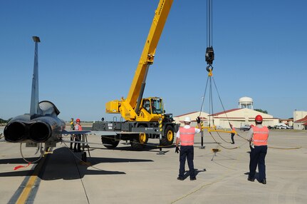 Jim Thomas (center) a supervisor with 12th Flying Training Wing maintenance, signals for a crane operator to begin raising a lifting sling into place during a T-38 trainer aircraft crash recovery exercise May 14 at Randolph Air Force Base, Texas. After the sling is attached to the aircraft, tension is placed on the cable,  but the aircraft is not actully lifted into the air. In an actual crash the aircraft would be lifted off  the runway.(U.S. Air Force photo/Dave Terry) (released)