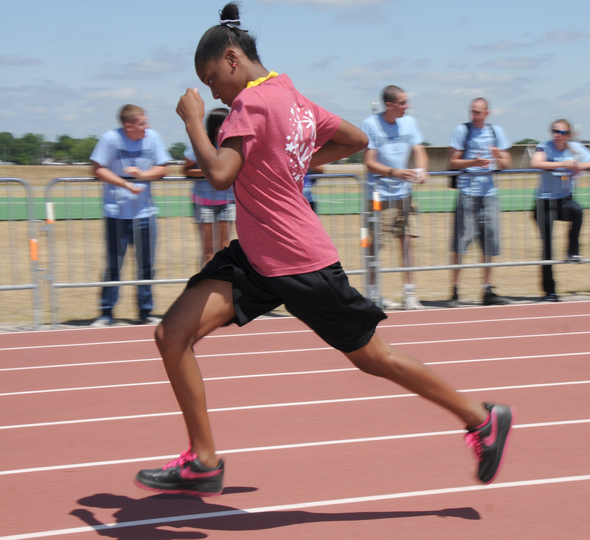 Athlete Diona Bell darts past a group of airmen sponsors to win the gold medal in the 100-meter run at Special Olympics, hosted by Keesler Friday and Saturday.  (U.S. Air Force photo by Kemberly Groue)