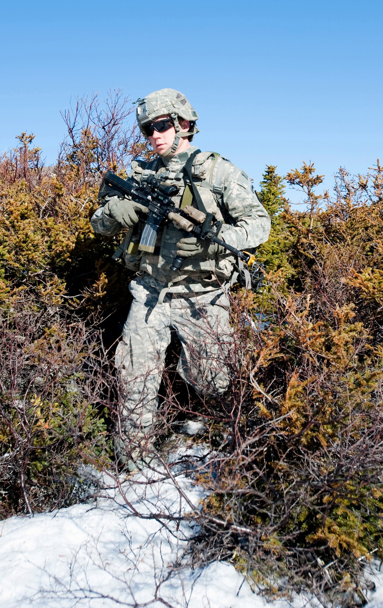JOINT BASE ELMENDORF-RICHARDSON, Alaska -- Spc. Colin Stallings of the Comanche Company, 1st Battalion, 501st Infantry Regiment (Airborne), makes his way through some brush while on patrol through Alaska's Chugach Range May 12. Soldiers took part in air assault training where UH-60 Black Hawk helicopters took them into a section of the mountain range and they were tasked with engaging an opposing force.  (U.S. Air Force photo/Senior Airman Christopher Gross)