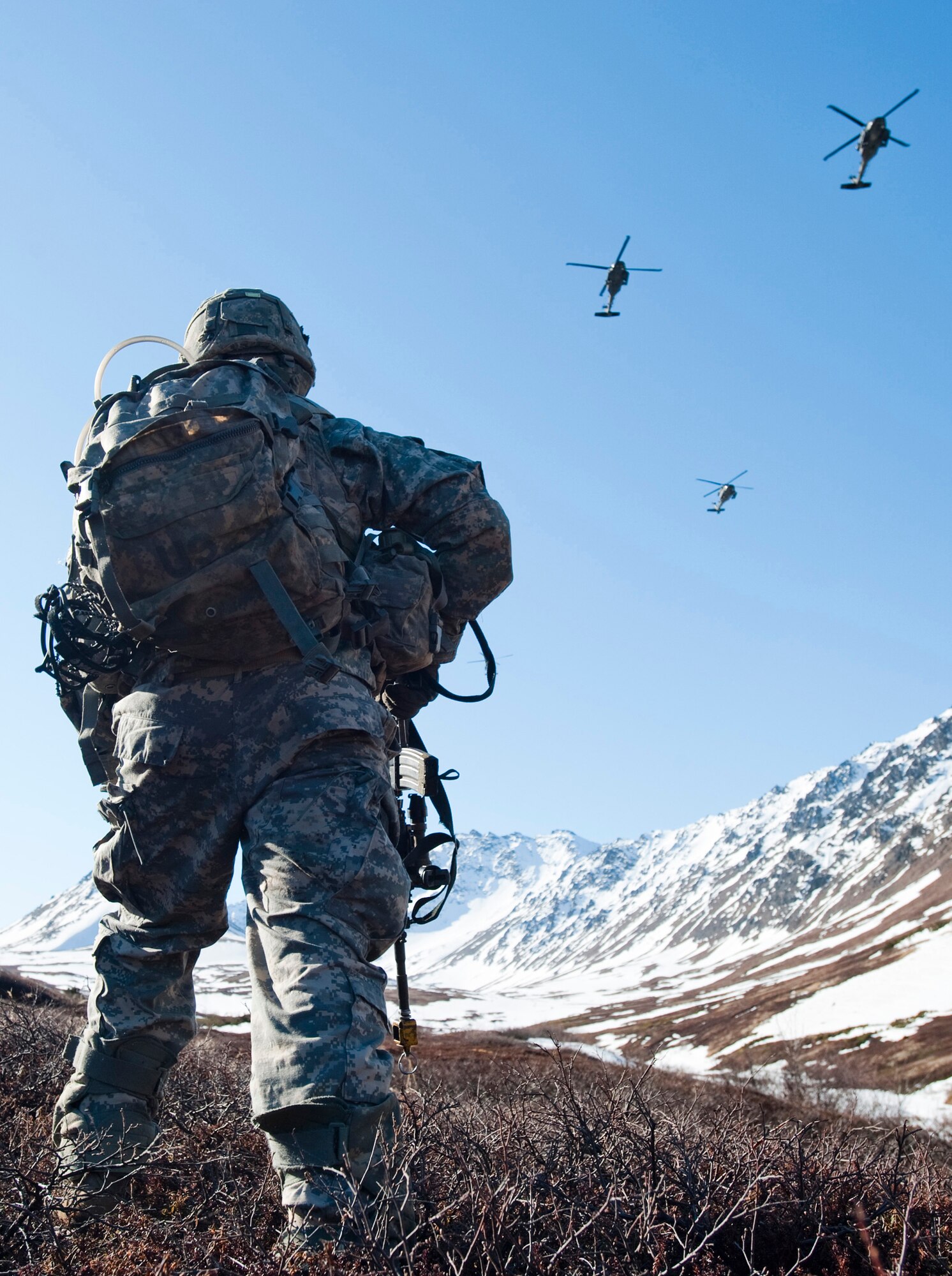 JOINT BASE ELMENDORF-RICHARDSON, Alaska -- Spc. Colin Stallings of the Comanche Company, 1st Battalion, 501st Infantry Regiment (Airborne), patrols through Alaska's Chugach Range as three UH-60 Black Hawk helicopters fly above him May 12. Soldiers took part in air assault training where Black Hawks took them into a section of the mountain range and they were tasked with engaging an opposing force.  (U.S. Air Force photo/Senior Airman Christopher Gross)