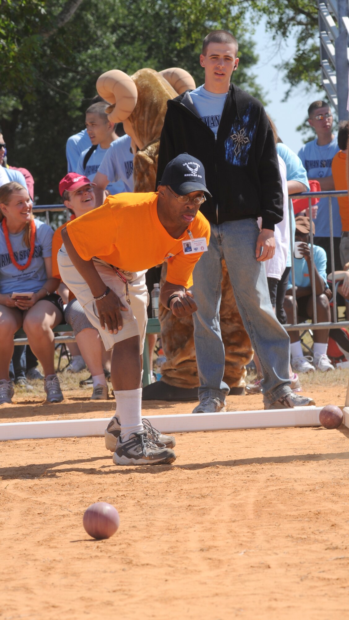 Athlete Perry Taylor takes his turn during the bocce ball competition as Airman Basic Tyler Deeds looks on. Airman Deeds, 332nd Training Squadron, is one of the Keesler students who served as sponsors for the athletes.  (U.S. Air Force photo by Kemberly Groue)