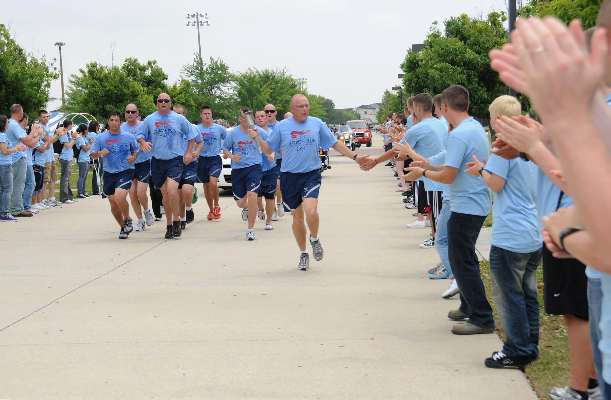 Team Keesler members cheer as Brig. Gen. Andrew Mueller, 81st Training Wing commander, carries the Olympic Torch down the troop walk accompanied by runners from the 81st Security Forces Squadron in preparation for the Mississippi Special Olympics Summer Games, Friday. It’s the 25th year that Keesler has hosted the statewide event. Opening ceremonies took place Friday night. Saturday’s athletic
competitions were followed by a victory dance. More than 1,200 athletes and coaches and 3,000 volunteers joined forces to make the weekend a success.  (U.S. Air Force photo by Kemberly Groue)