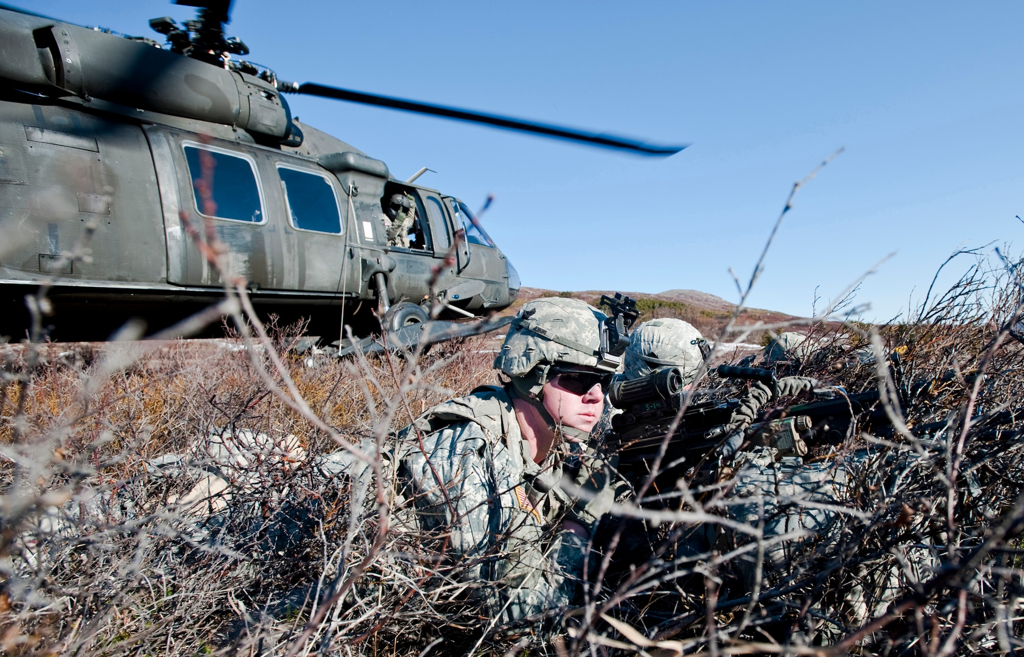 JOINT BASE ELMENDORF-RICHARDSON, Alaska -- Soldiers of Comanche Company, 1st Battalion, 501st Infantry Regiment (Airborne), watch for the "enemy" in the area while their UH-60 Black Hawk helicopter takes off May 12. The Soldiers took part in air assault training where Black Hawks took them into a section of Alaska's Chugach Range and they were tasked with engaging an opposing force. (U.S. Air Force photo/Senior Airman Christopher Gross)