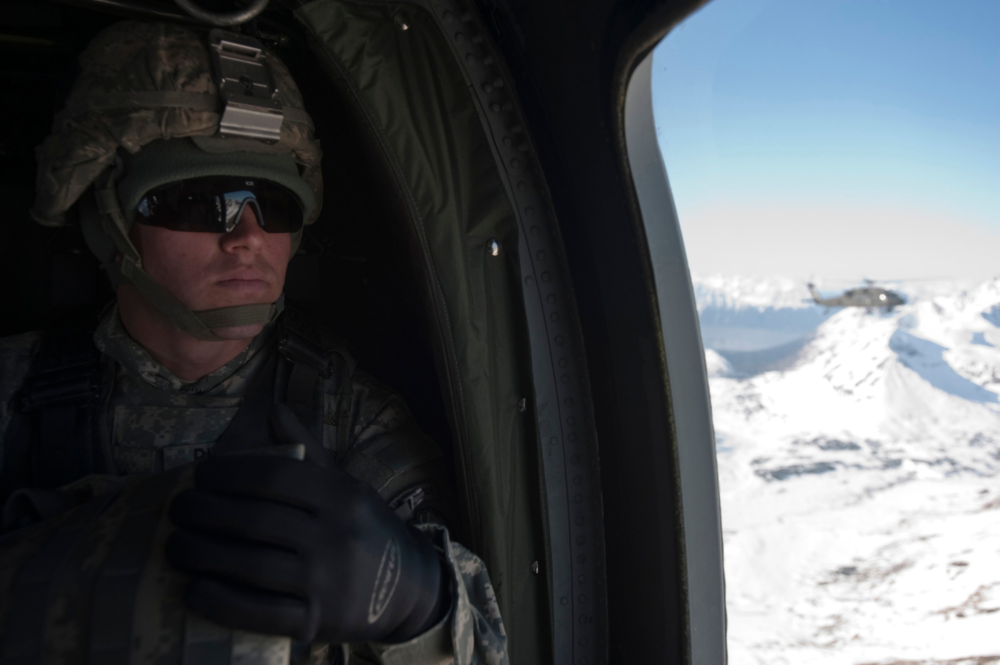JOINT BASE ELMENDORF-RICHARDSON, Alaska -- Pvt. Adrian Russell of the Comanche Company of the 1st Battalion, 501st Infantry Regiment (Airborne) sits and waits to take part in an air assault training mission while another UH-60 Black Hawk helicopter flies over Alaska's Chugach Mountain Range May 12. Soldiers from the company were taken into a section of mountains and tasked with engaging an opposing force. (U.S. Air Force photo/Senior Airman Christopher Gross)JOINT BASE ELMENDORF-RICHARDSON, Alaska ? Pvt. Adrian Russell of the 3rd Platoon, Comanche Company, 1st Battalion, 501st Infantry Regiment (Airborne), sits and waits to take part in an air assault while another UH-60 Black Hawk helicopter flies over Alaska?s Chugach Range May 12. Soldiers from the company were taken into a section of mountains and tasked with engaging an opposing force. (U.S. Air Force photo/Senior Airman Christopher Gross)