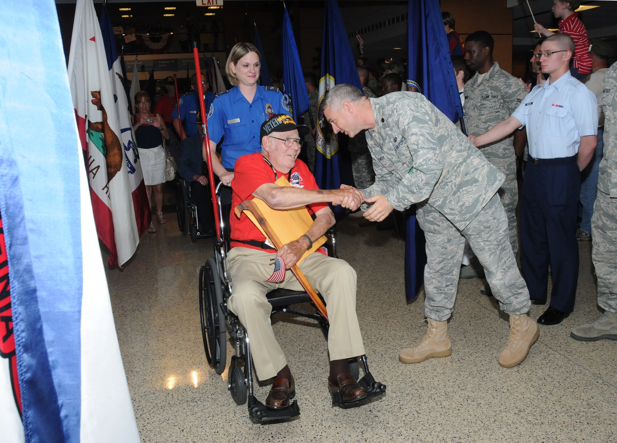 Douglas Anderson, a World War II Navy veteran from Pascagoula, is welcomed home by Lt. Col. Michael Callender, 334th Training Squadron commander, from Mississippi’s first Honor Flight to Washington, D.C., May 11 at the Gulfport-Biloxi International Airport.  Airport security officer Kathryn Morong guides Mr. Anderson through the welcoming crowd.  Mr. Anderson and 90 other war veterans, who passed through an aisle of state flags held by Keesler students at the airport, visited the World War II Memorial and other sites in the nation's capital.  (U.S. Air Force photo by Kemberly Groue)