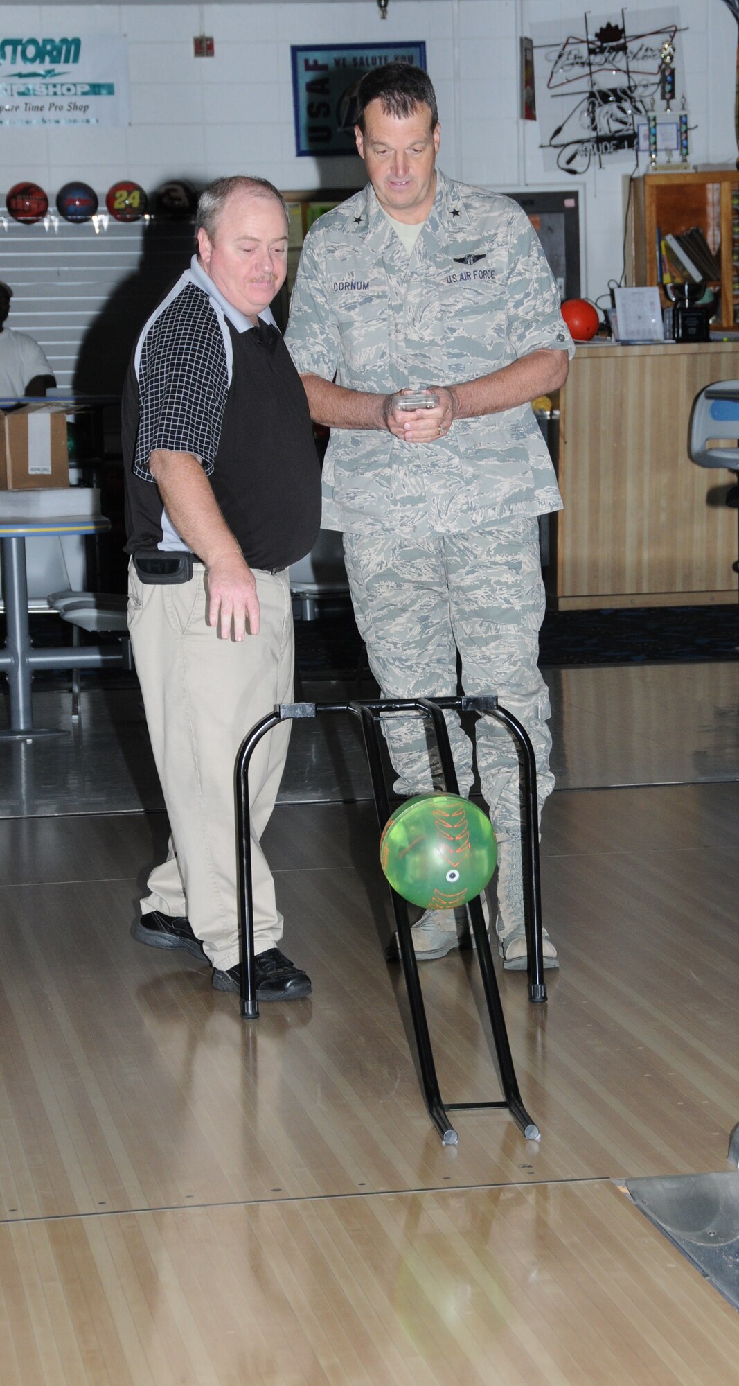 Mr. Bosarge, left, gives Brig. Gen. Kory Cornum, 81st Medical Group commander, a quick lesson on how to operate the RC900 remote-controlled bowling ball.  (U.S. Air Force photo by Kemberly Groue)