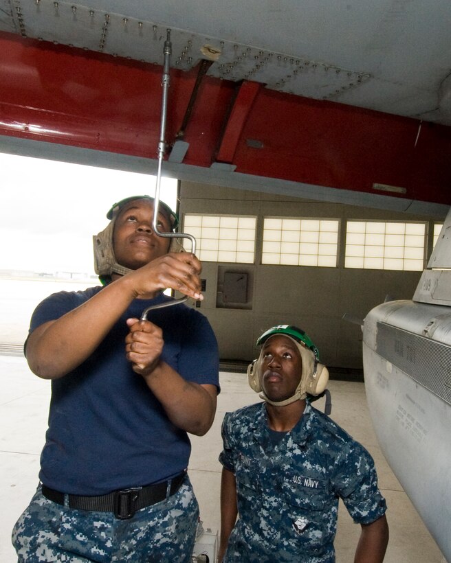 Navy aviation mechanic Kandice Jones, installs phase B panels on the leading edge of the forward port wing of a squadron C-130 aircraft, as Navy aviation mechanic Aaron Hunt observes May 17. Both aircrew members are assigned to Navy Fleet Logistics Squadron 53 here. (Photo by Bobby Jones)
