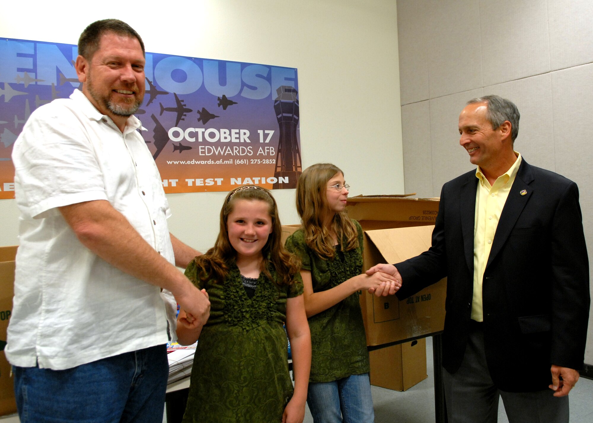 Danny Bazzell, (far left) Edwards AFB Civilian Military Support Group vice president and Mike Belzil (far right) Edwards AFB Civilian Military Support Group president present Civ-Mil coins to Shayla Smith (left) and Brittany Sheridan for their work in collecting over 5,000 for deploying troops. (Air Force photo by Kate Blais)