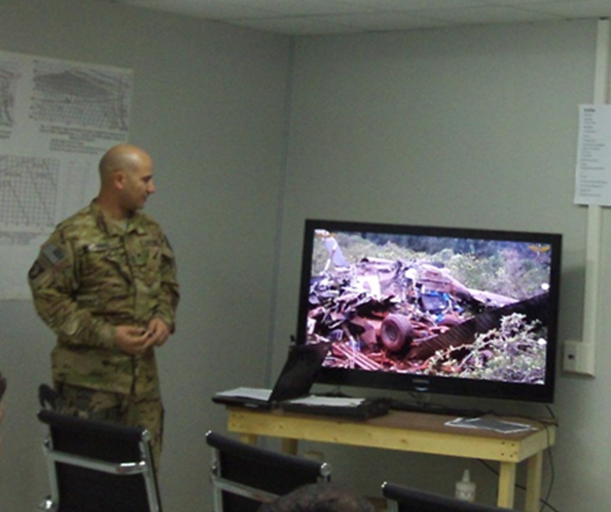Sergeant First Class Clinton Bruce, 159th Combat Aviation Brigade non-rated crewmember standardization instructor, shows Afghan Air Force pilots and aircrew members pictures of a UH-60 mishap during an aircrew coordination training class May 14 at Kandahar Airfield. The ACT class is a three-part course that is designed to help improve the communication between pilots and their crews. (U.S. Air Force courtesy photo)
