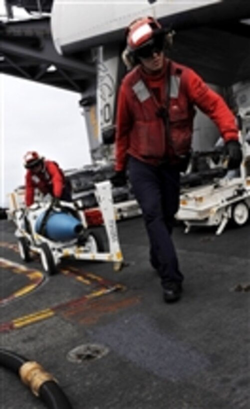 Petty Officer 2nd Class Jeffrey Anderson (right) and Petty Officer 1st Class Michael Washa move ordnance on the flight deck of the aircraft carrier USS John C. Stennis (CVN 74) in the Pacific Ocean on May 13, 2011.  The John C. Stennis Carrier Strike Group is participating in a composite training unit exercise off the coast of southern California.  
