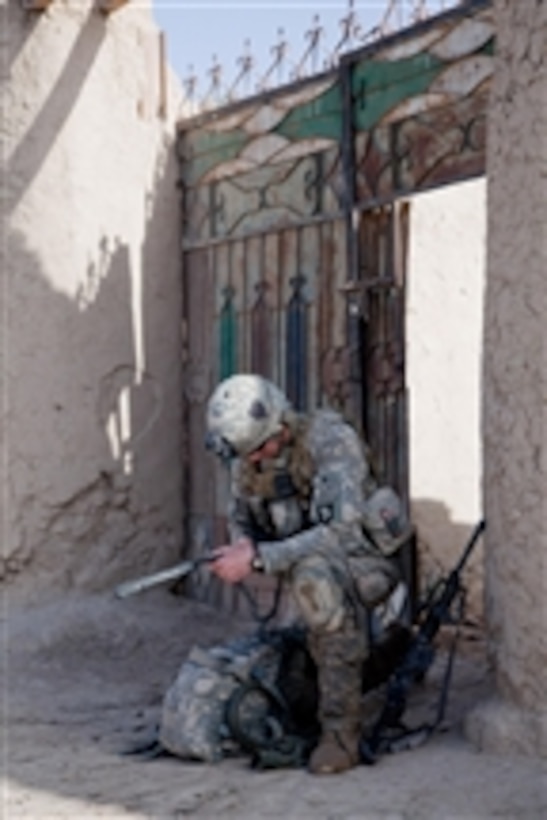 A U.S. Army soldier with Alpha Company, 2nd Battalion, 502nd Infantry Regiment, 101st Airborne Division, takes a knee to check his radio while on patrol near Nalgham, in Kandahar province, Afghanistan, on April 21, 2011.  
