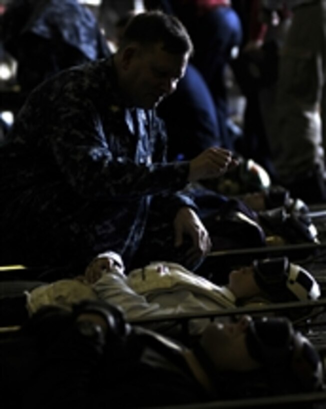 Chaplain Lt. Cmdr. James West prays for sailors during a mass casualty drill in the hangar bay of the aircraft carrier USS Carl Vinson (CVN 70) in the Strait of Malacca on May 11, 2011.  The Carl Vinson and Carrier Air Wing 17 are underway in the U.S. 7th Fleet area of responsibility.  