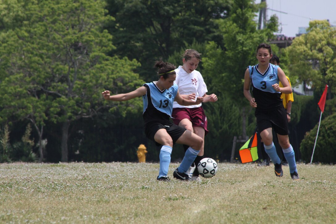 Iray Hylton, an Osan American High School girls soccer team midfielder, attempts to return the ball to Osan players by blocking Madison Byers, a Matthew C. Perry High School girls soccer team defender, and kicking the ball out of M.C. Perry possession at the M.C. Perry High School soccer field here during the Department of Defense Dependent Schools 2011 Division II Far East Girls Soccer Tournament championship game May 19. Osan and Perry played each other in three games throughout the two-day, double elimination tournament. Perry beat Osan 1-0 in the first game, while Osan beat Perry in the second and the third game ended in a regulation tie 0-0. Osan won the championship 2-1 during penalty kicks.