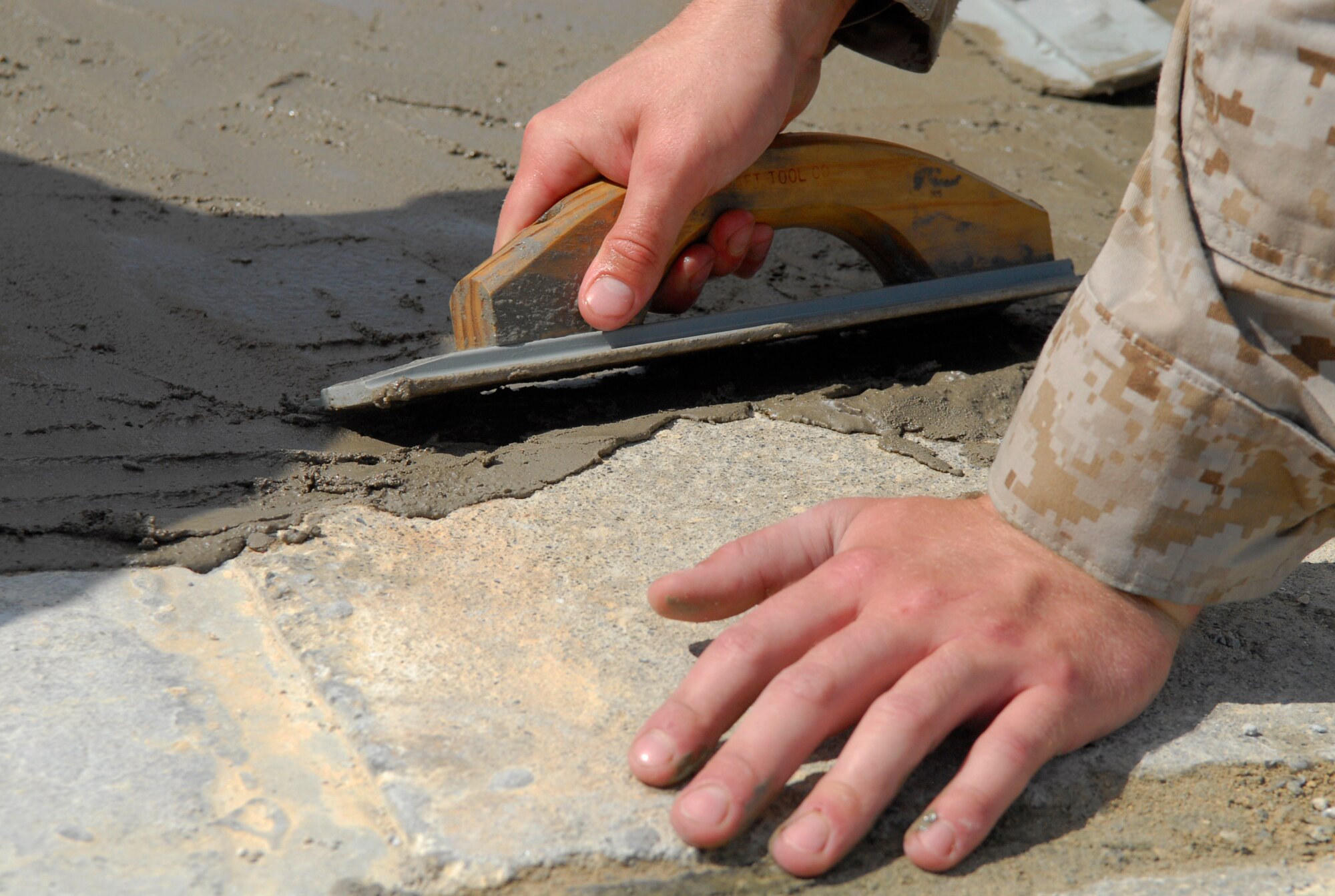 Marines assigned to Camp Foster's Marine Wing Support Squadron 172 smooth quick-drying cement as they work against the clock to repair spalled concrete at Kadena's Silver Flag site. The air base's 554th RED HORSE Squadron hosted a week-long training camp for the Marines, teaching techniques in heavy equipment operation and rapid runway repair methods unique to the Air Force. (U.S. Air Force photo/Airman 1st Class Tara A. Williamson)