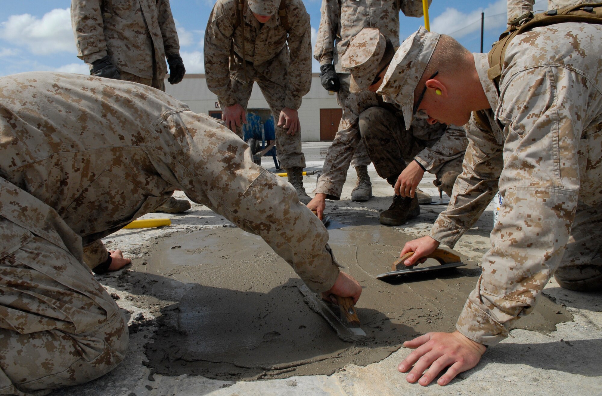 Marines assigned to Camp Foster's Marine Wing Support Squadron 172 smooth quick-drying cement as they work against the clock to repair spalled concrete at Kadena's Silver Flag site. The air base's 554th RED HORSE Squadron hosted a week-long training camp for the Marines, teaching techniques in heavy equipment operation and rapid runway repair methods unique to the Air Force. (U.S. Air Force photo/Airman 1st Class Tara A. Williamson)