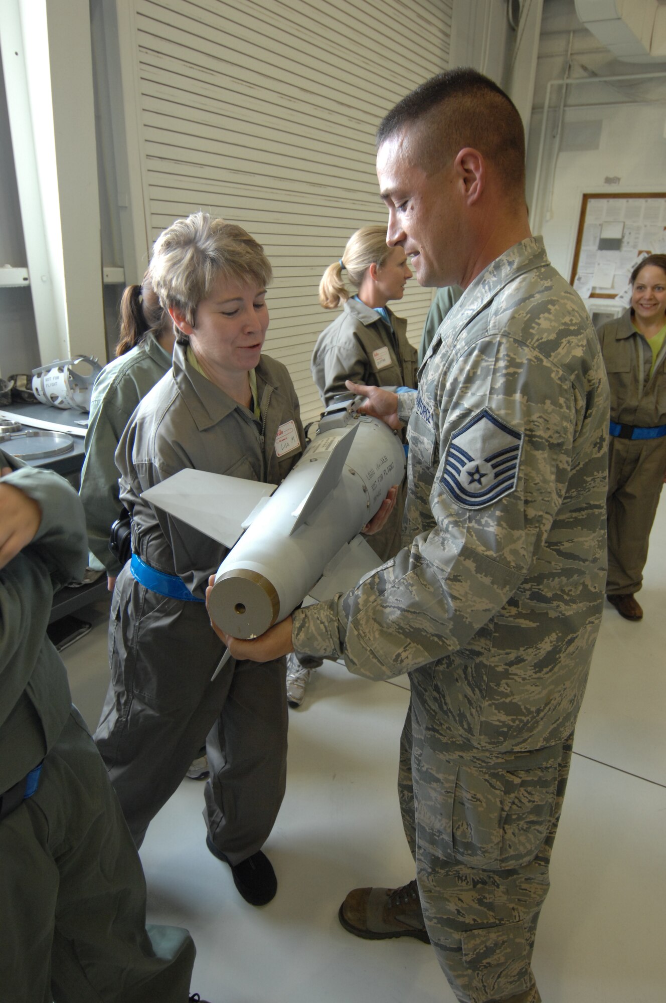 MOUNTAIN HOME AIR FORCE BASE, Idaho – Master Sgt. Robert P. Maack, 366th   Equipment Maintenance Squadron munitions inspector, gives Lisa McClellan an opportunity to hold the tail end of a Ground Busting Unit-31 Joint Direct Attack Munition, in order to get an idea of how much that particular piece of the munition weighs. The spouses of senior wing staff were given a demonstration of how the munitions were assembled and the capabilities of the munitions during a tour May 16. (U.S. Air Force photo by Senior Airman Benjamin Sutton)