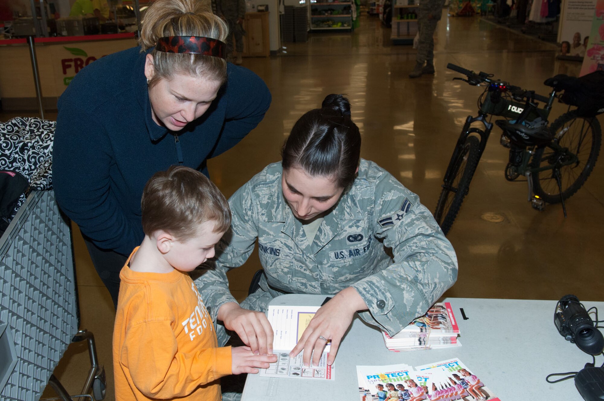 HANSCOM AIR FORCE BASE, Mass. – Airman 1st Class Jessica Jenkins (right) takes the fingerprints of Benjamin Elton Jr. as Anna Elton watches. As part of Police Week, fingerprinting was available in the BX atrium May 10. The 66th Security Forces Squadron hosted many demonstrations, events and activities for Police Week May 9 through 13. Money raised during the week was given to the Air Force Security Police Association and the Domestic Violence Services Network. (U.S. Air Force photo by Rick Berry)