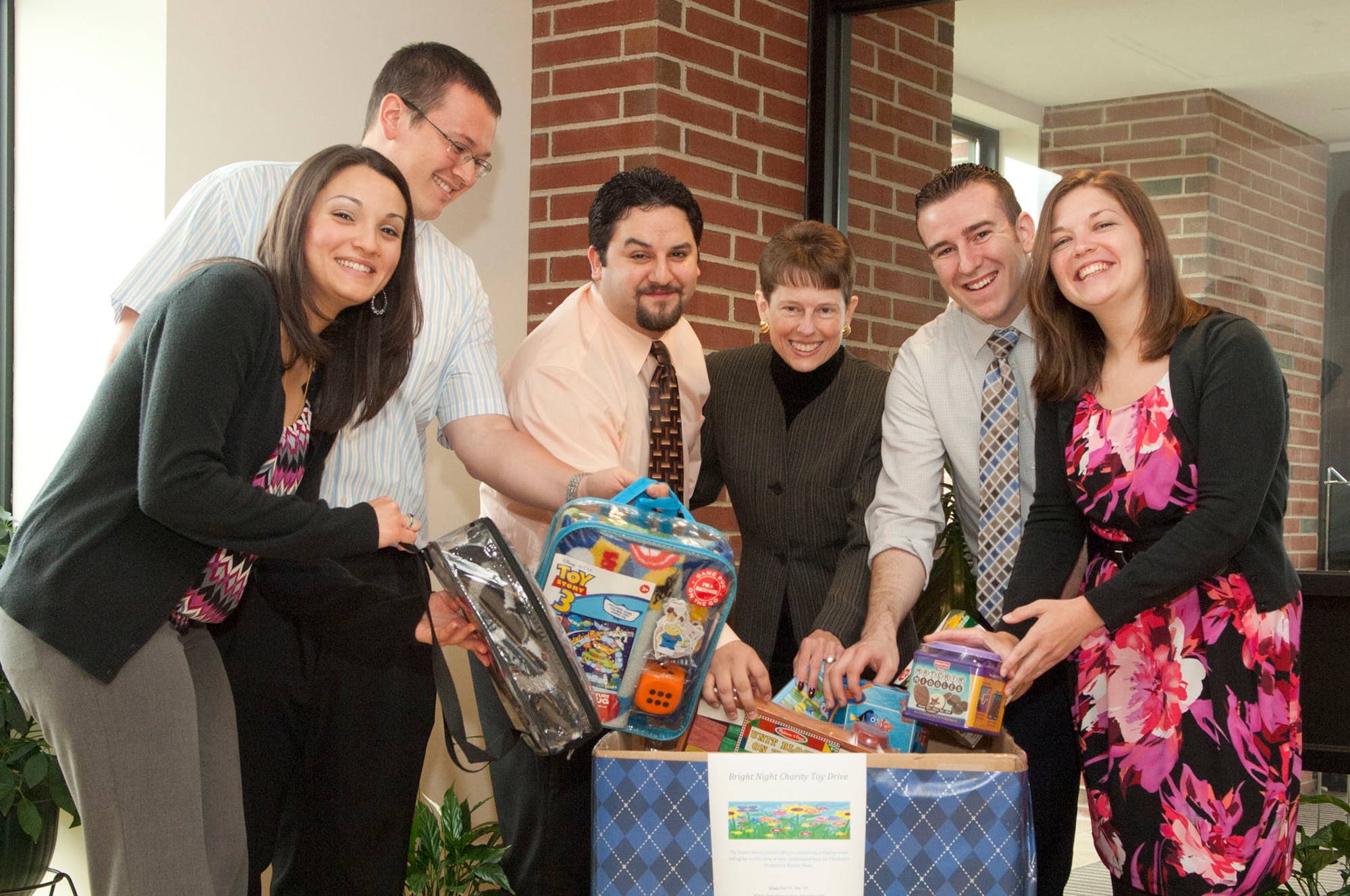 HANSCOM AIR FORCE BASE, Mass. - Krystal McPhillips, Patrick McPhillips, Paul Pollard, Susan Cunningham, Dan Lavoie and Jennifer Carrion (left to right) drop toys in a bin for the Bright Night Charity Toy Drive. The toy drive, sponsored this year by the Junior Force, Company Grade Officers and PK Interns councils, kicked off this week at the donation bin in the Building 1604 lobby. The organizations are collecting gifts to brighten the nights – and days – of seriously ill children at Children’s Hospital in Boston.  (U.S. Air Force photo by Mark Wyatt)