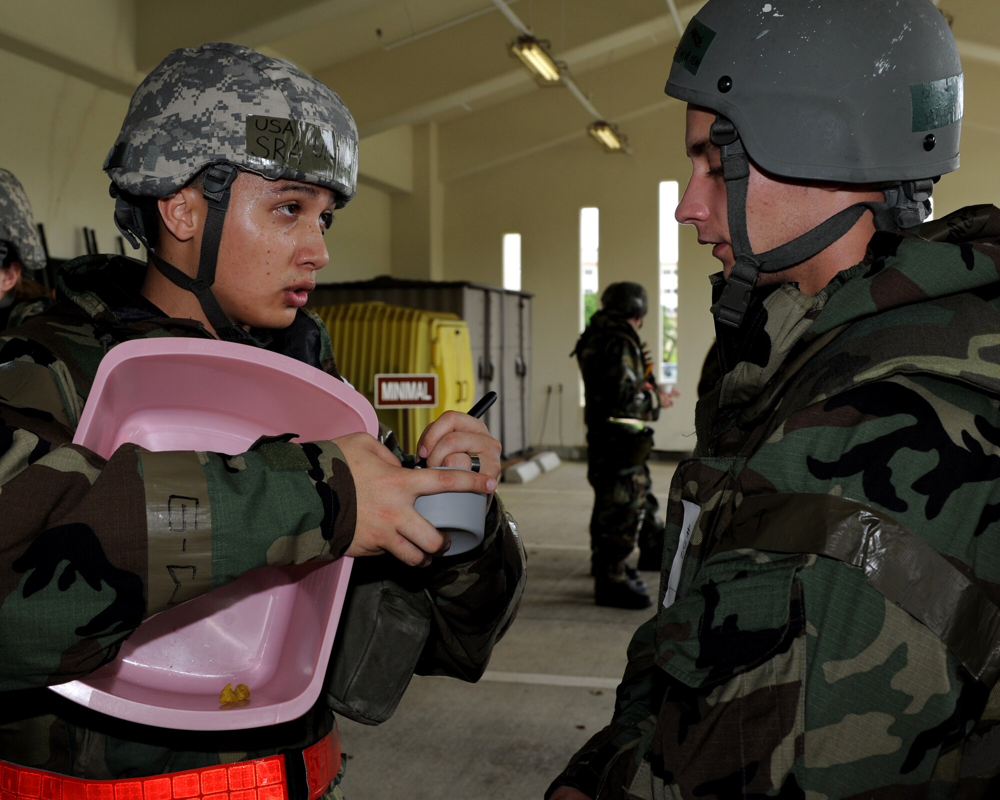 Staff Sgt. Uriah Poore (left), 18th Medical Support Squadron, passes a stool sample container to an airman who is simulating being treated after having food poisoning as part of local operational readiness exercise Beverly High 11-4, May 19, at Kadena Air Base, Japan. Kadena's personnel are participating in the LORE to stay prepared for real world contingencies. (U.S. Air Force photo/Junko Kinjo)
