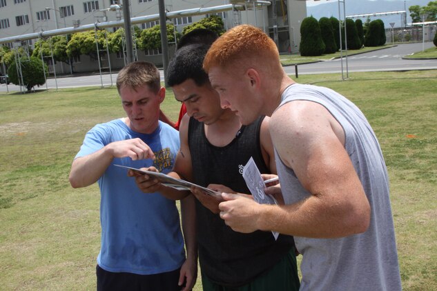 Vonace Creswellmcdermett (LEFT), Adam Santana Jr. and Justan Browning, Beast Mode team members, attempt to find the difference between the picture and the scene in front of them at the field in front of Barracks 314 here during the 2011 Amazing Race May 20. This station was one of 14 stations with different activities.