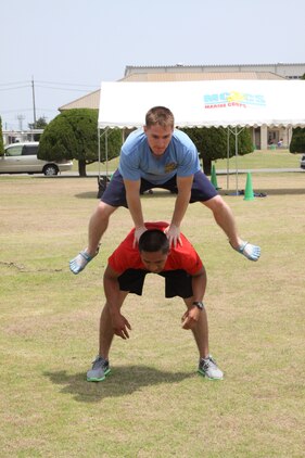 Vonace Creswellmcdermett, Beast Mode team member, jumps over Israel Martinez, Beast Mode team member, at the leapfrog section of the parade deck station here during the 2011 Amazing Race May 20. The two team members bound over each other as fast as they could without getting hurt to complete their portion of the three section station.