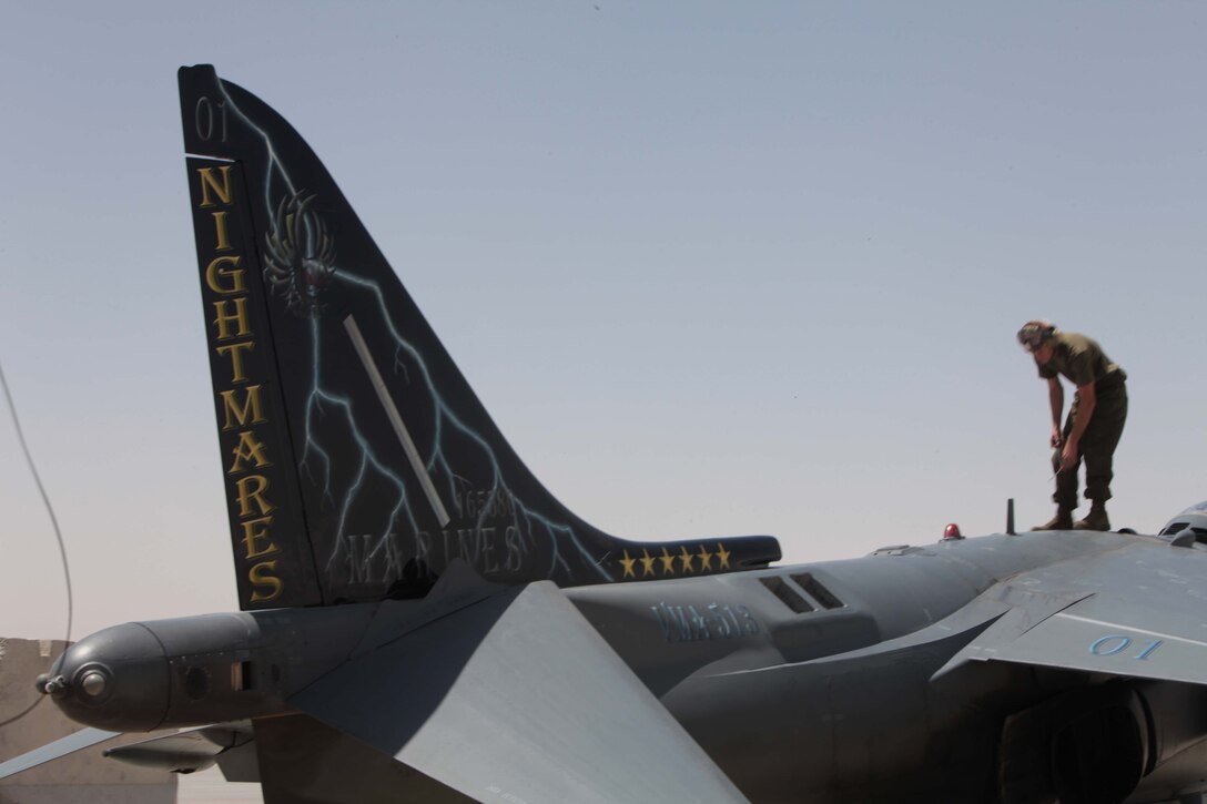 Cpl. Michael Bybee, a Marine Attack Squadron 513 powerline mechanic and Garden Grove, Calif., native, works atop the AV-8B Harrier numbered “01,” which bares Sgt. Edwardo Amor’s artwork on its tail, on the flightline of Kandahar Airfield, Afghanistan, May 20. Amor, a VMA-513 airframes mechanic and Dallas native, painted the tail shortly before his artwork debuted in Afghanistan.
