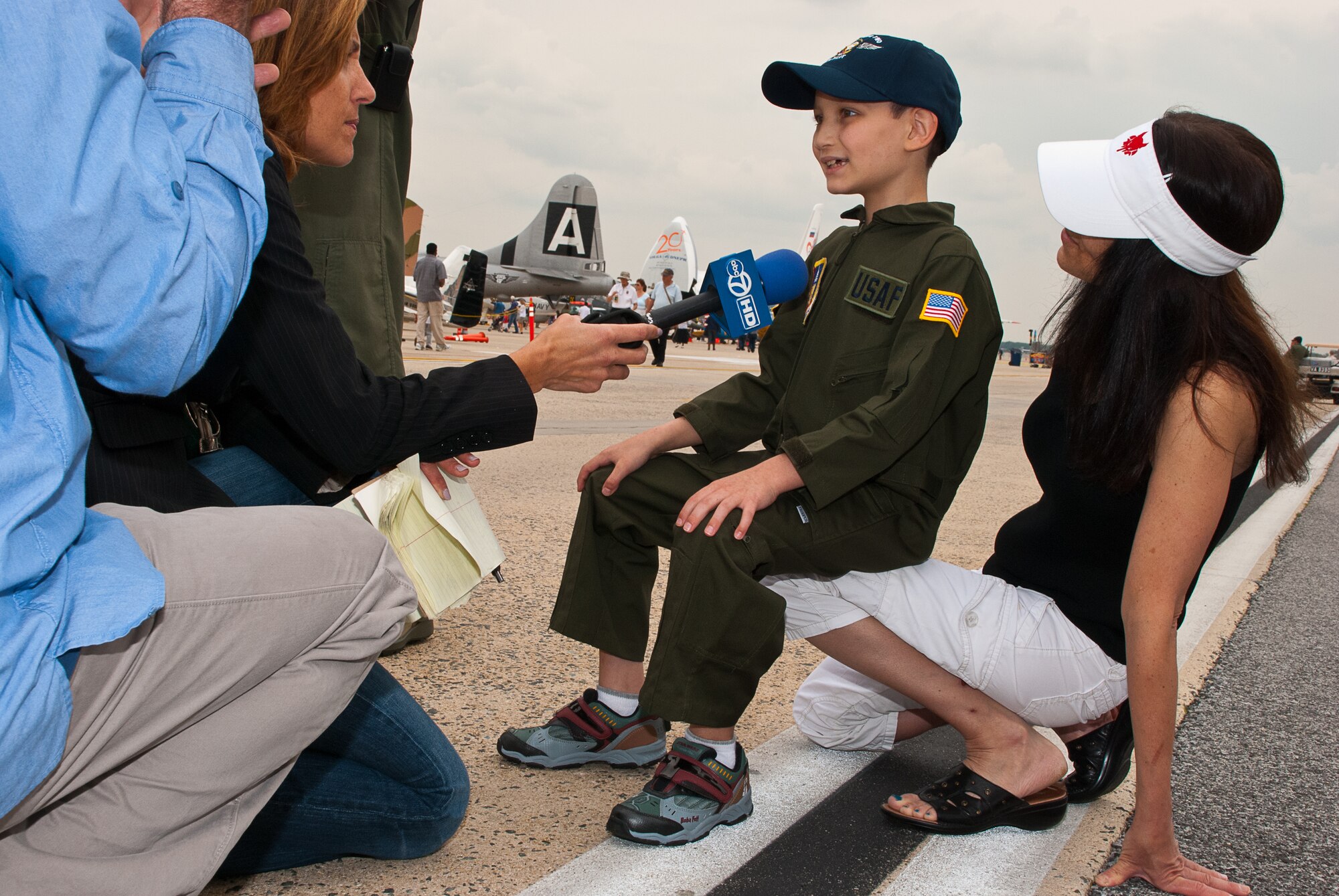 JOINT BASE ANDREWS, Md. -- Brandon Leach, eight, Pilot for a Day alum, sits on his mother, Suzie's knee, while being interviewed by a television reporter, at the Joint Service Open House here May 20. The 201st Airlift Wing, the 113th Wing and the 459th Air Refueling Wing sponsored a Pilot for a Day 2011 reunion during the JSOH. The Pilot for a Day program offers children serious illnesses a special day to be an Air Force pilot, giving them a break from whatever challenges they may face. (U.S. Air Force photo/ Staff Sgt. Sophia Piellusch)