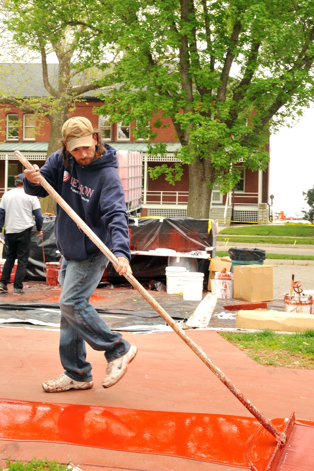 OFFUTT AIR FORCE BASE, Neb. -- Shawn Gladen of Bynon Sports, spreads top coat to be used as primer before laying a rubber surface on the track around the parade field at Offutt Air Force Base on May 18.  Bynon Sports, which is located in Hunt Valley, Maryland was contracted to cover the concrete track at the Offutt parade field with a rubber surface. U.S. Air Force Photo by D.P. Heard
