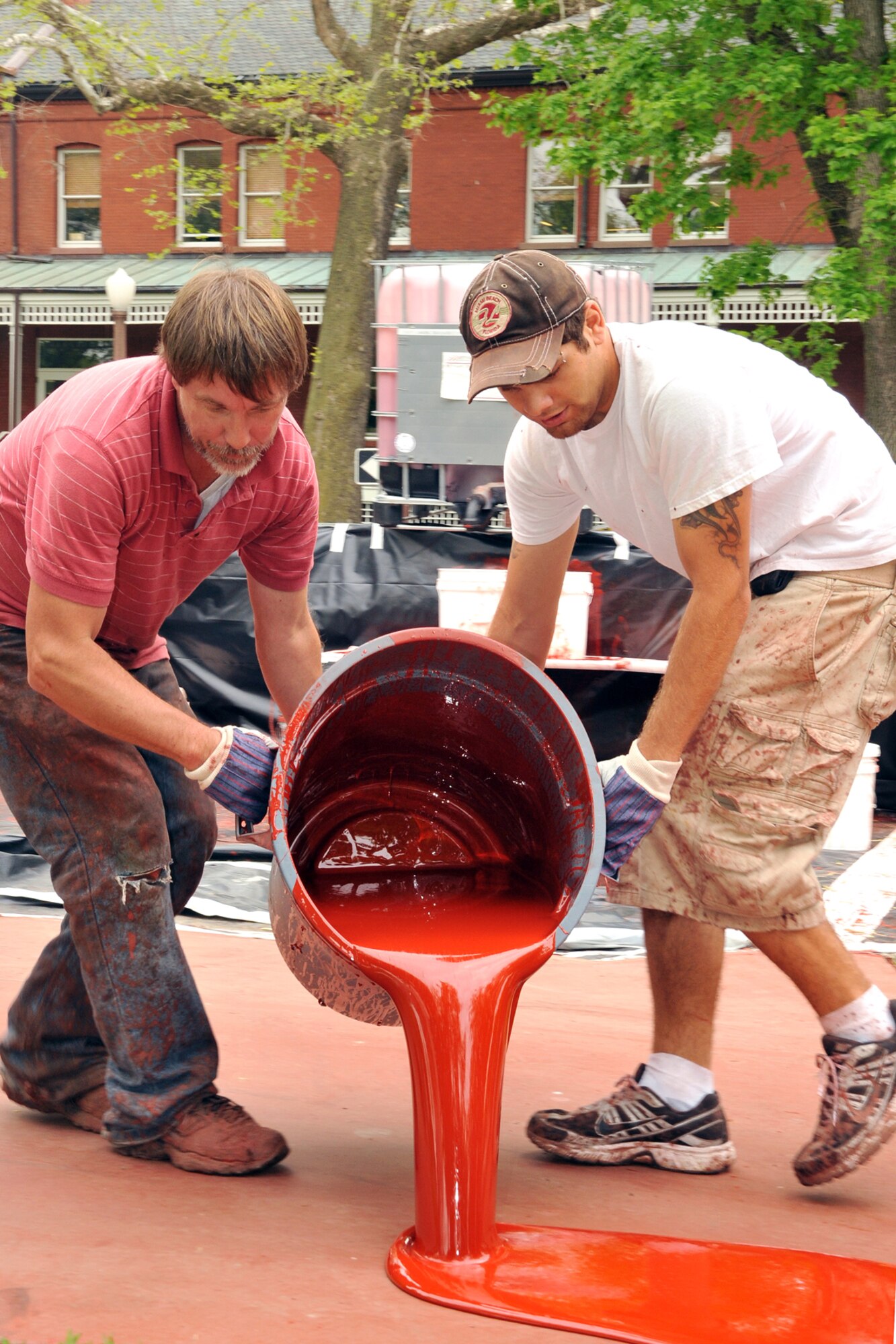 OFFUTT AIR FORCE BASE, Neb. -- Shawn Gladen of Bynon Sports, spreads top coat to be used as primer before laying a rubber surface on the track around the parade field at Offutt Air Force Base on May 18.  Bynon Sports, which is located in Hunt Valley, Maryland was contracted to cover the concrete track at the Offutt parade field with a rubber surface. U.S. Air Force Photo by D.P. Heard
