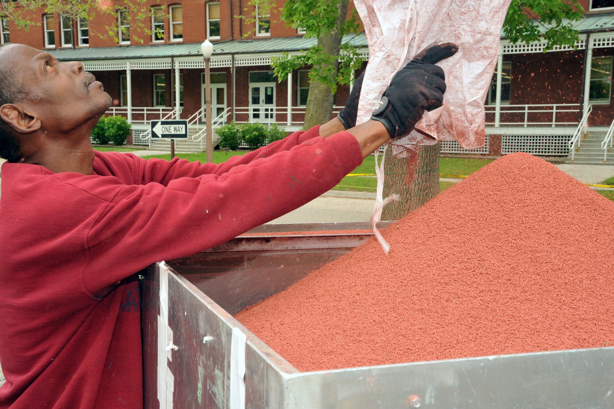 OFFUTT AIR FORCE BASE, Neb -- Gene Degraffenreaid of Bynon Sports,  guides the bag that dispenses rubber particles into a wheel barrel at parking lot adjacent to the parade field at Offutt Air Force Base on May 18.  Bynon Sports, which is located in Hunt Valley, Maryland was contracted to cover the concrete track at the Offutt parade field with a rubber surface. U.S. Air Force Photo by D.P. Heard
