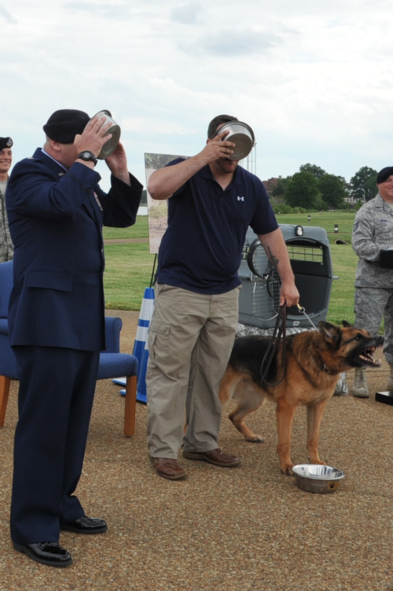 Lt. Col Scott Foley, 633d Security Forces Squadron commander, and retired Staff Sgt. Chris Rocchio, 633d SFS Dog Handler, drink out of dog bowls during Argo’s, 633d SFS Military Working Dog, retirement ceremony as part of a tradition during National Police Week at Langley Air Force Base, Va., May 20, 2011. The National Police Week pays special recognition to law enforcement officers, civilian and military. (U.S. Air Force photo by Airman 1st Class Camilla Griffin)(RELEASED)