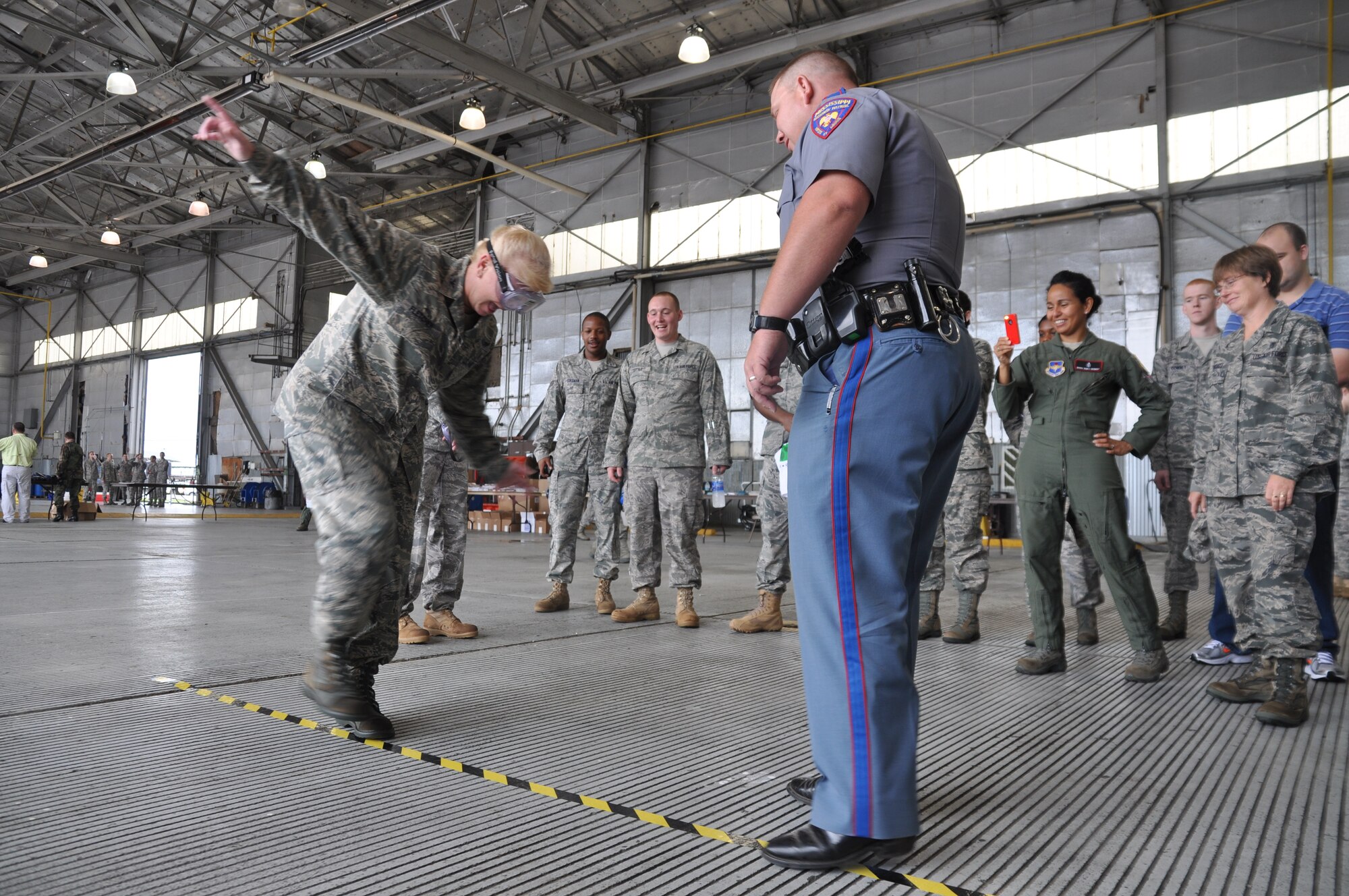 Col. Diane Fletcher, 14th Medical Group Commander, voluntarily demonstrates the effects of alcohol on coordination as State Trooper Brian Mobley, Mississippi Highway Patrol Public Affairs Officer shows her a common test used to determine alcohol influence. Many other educational opportunities from car and motorcycle driving to public health were available at Back-2-Blaze Day. (U.S. Air Force photo/Airman 1st Class Chase Hedrick)