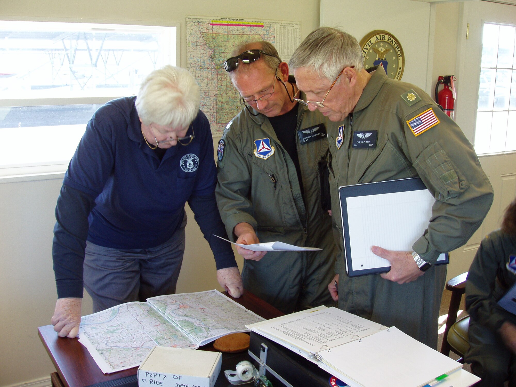 (From left) Maj. Esther Grupenhagen, Gateway Senior Squadron, briefs Kansas Wing aircrew 1st Lt. Darren MacDowell and Maj. Carl McElwee, both of the New Century Composite Squadron, about their first flight of the day.(Civil Air Patrol photo by Lt. Col. David A. Miller)