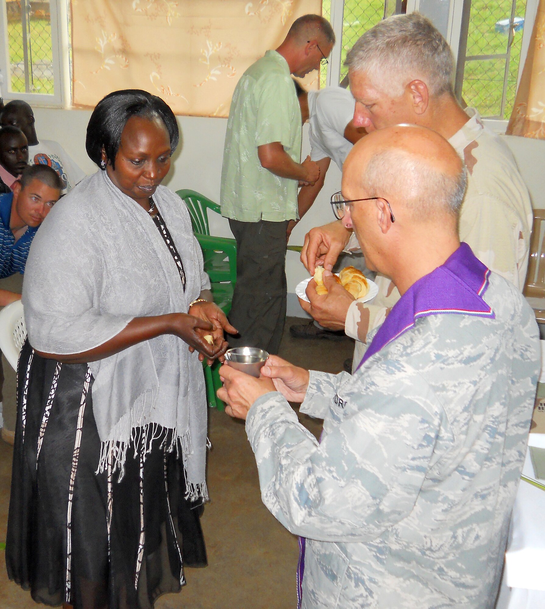 Rose Kagyinea, a contractor supervisor at Camp Kesenyi, Uganda, prepares to take Communion on Palm Sunday at the camp. Combined Joint Task Force-Horn of Africa Chaplain (Lt. Col.) David Terrinoni, bottom right, and Chaplain (Cmdr.) Stephen Beyer led the service for members of the CJTF-HOA cadre, U.S. Embassy personnel and Ugandan Peoples Defense Force soldiers. (Air Force photo by Maj. Khalid Cannon)
