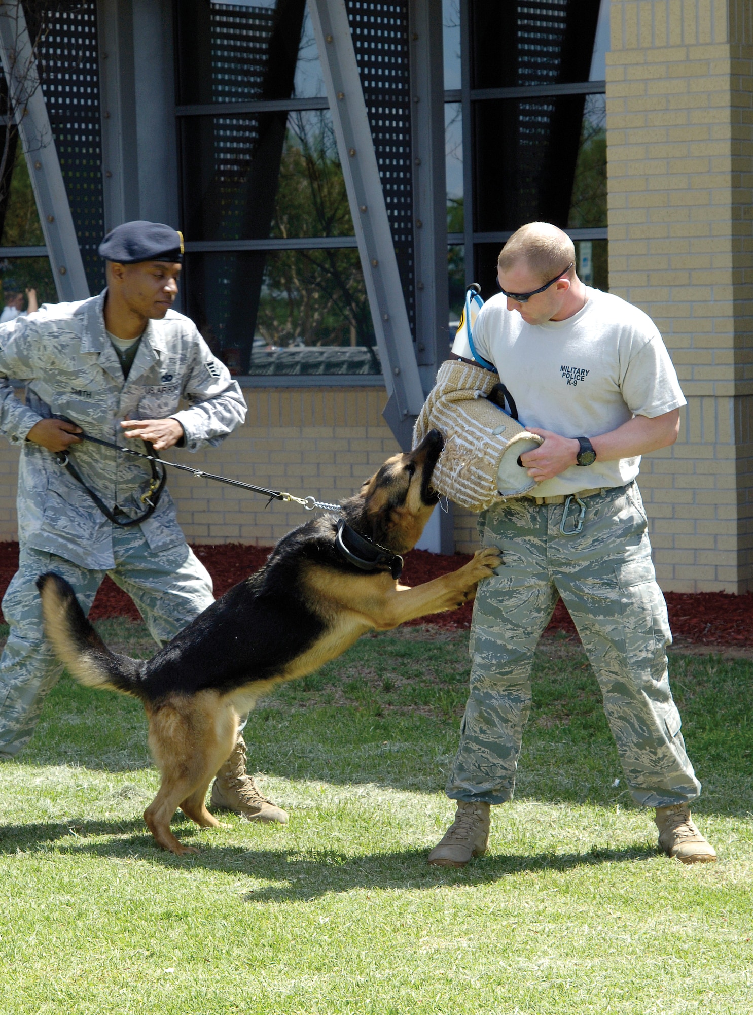 Staff Sgt. Tyshawn Smith and his Military Working Dog Rex, show a team’s abilities at the Exchange May 16 as part of the 72nd Security Forces Squadron-sponsored Police Week activities.  MWD handler Staff Sgt. James Cockhran wears a protective sleeve during the demonstration. (Air Force photo by Margo Wright)